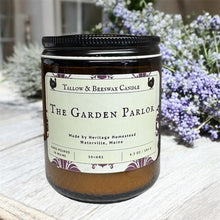Load image into Gallery viewer, Tallow and beeswax candle labeled 'The Garden Parlor' on a wooden surface with flowers in the background.