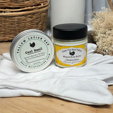 Load image into Gallery viewer, Two containers of body care products on a wooden surface with a white cloth and wicker basket in the background.