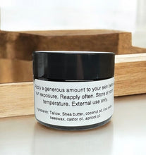 Load image into Gallery viewer, Tallow sun balm 2 oz amber Jar with black lid and white label on a wooden surface