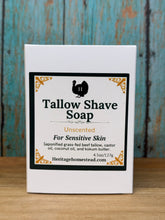 Load image into Gallery viewer, A white rectangular box of Tallow Shave Soap, Unscented, placed on a rustic blue wooden surface next to a light wood background. The box features a black and gold label with a silhouette of a turkey.