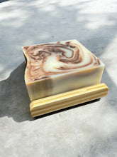Load image into Gallery viewer, Naturally moisturizing tallow soap bar lavender cow colored with cocoa powder and lavender essential oils laying on a soap rest (Soap rest not included with Soap bar purchase)