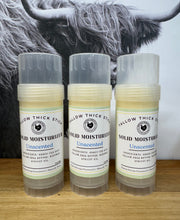 Load image into Gallery viewer, Three containers of Tallow Thick Stick solid moisturizer on a wooden surface with a blurred background of a cow.