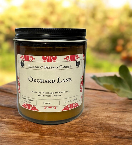 tallow and beeswax Candle labeled 'Orchard Lane' on a wooden surface with a blurred natural background