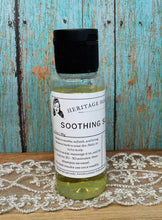 Load image into Gallery viewer, A bottle of Heritage Hair Soothing Scalp Treatment with a black cap and white label, set on a wooden surface with a lace cloth and distressed blue wooden background.
