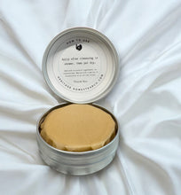 Load image into Gallery viewer, Bar of soap in a metal tin with instructions on a white fabric background
