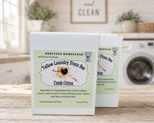 Load image into Gallery viewer, Two white boxes of Heritage Homestead Tallow Laundry Stain Bar in Fresh Citrus scent, displayed on a wooden table with a blurred kitchen and washing machine background.

