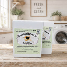 Load image into Gallery viewer, Two white boxes of Heritage Homestead Tallow Laundry Stain Bar in Fresh Citrus scent, displayed on a wooden table with a blurred kitchen and washing machine background.
