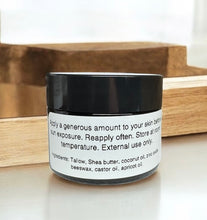 Load image into Gallery viewer, Tallow sun balm 2 oz amber Jar with black lid and white label on a wooden surface 
