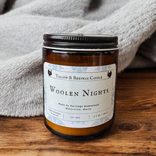 Load image into Gallery viewer, Tallow and beeswax Candle labeled 'Woolen Nights' on a wooden surface with a gray towel in the background
