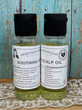 Load image into Gallery viewer, Two clear plastic bottles of Heritage Homestead Soothing Scalp Oil with black caps and white labels, displayed side-by-side on a lace cloth against a rustic blue wooden background.
