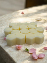 Load image into Gallery viewer, Hexagonal beeswax wax melts on a textured surface with pink flowers.
